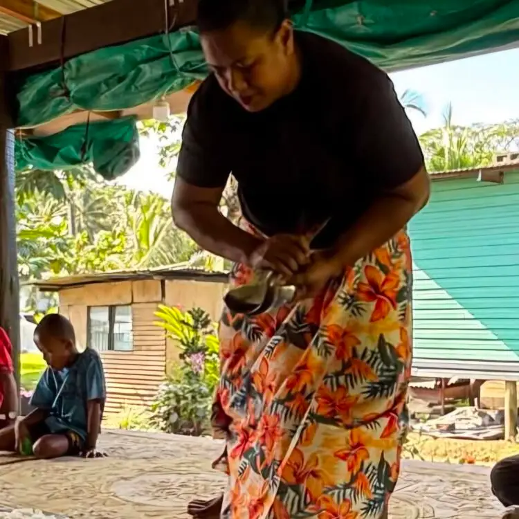 One of the village maidens fixes the utensils for lunch.